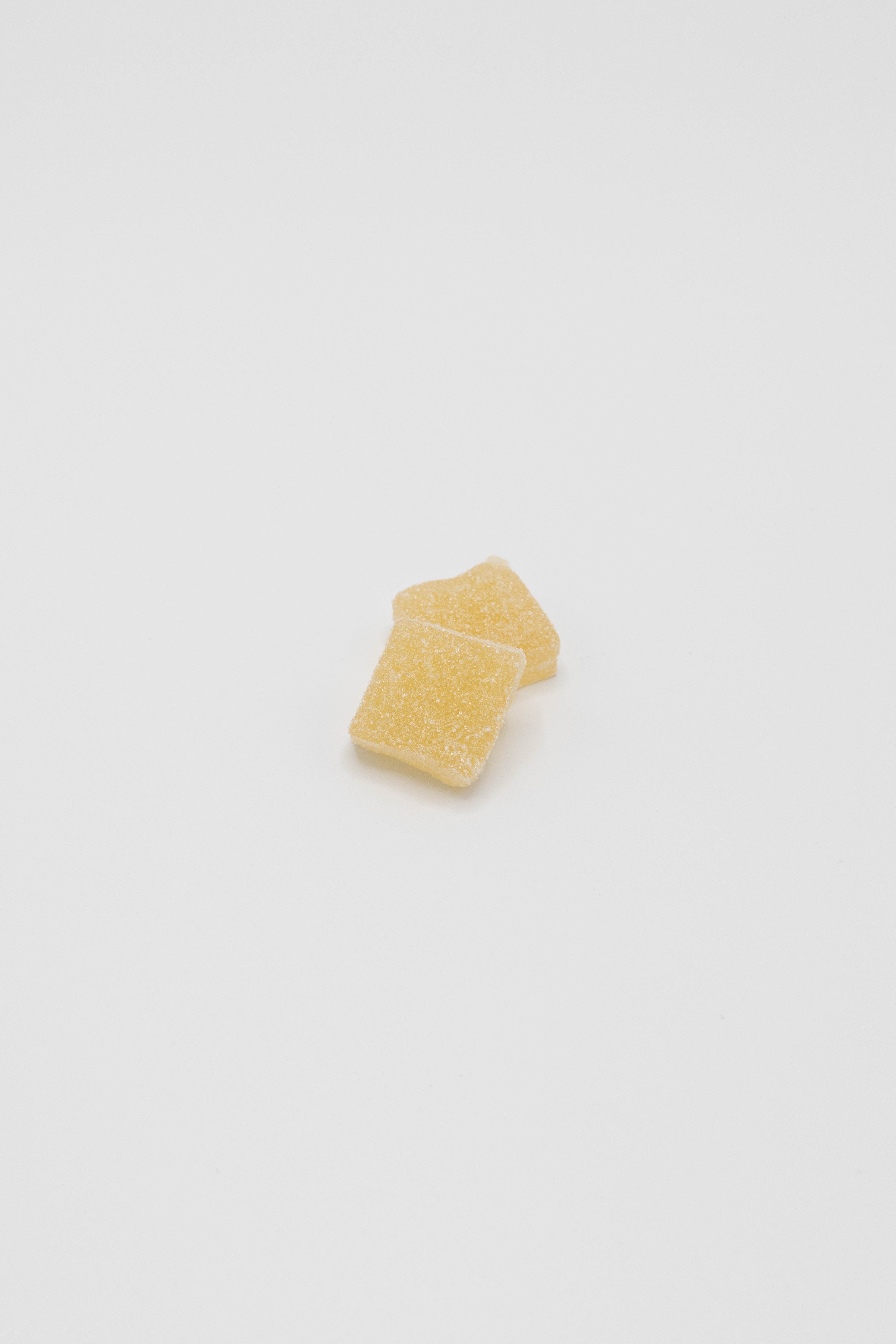 Two small, textured pale yellow square-shaped pieces stacked slightly offset on a plain white background.