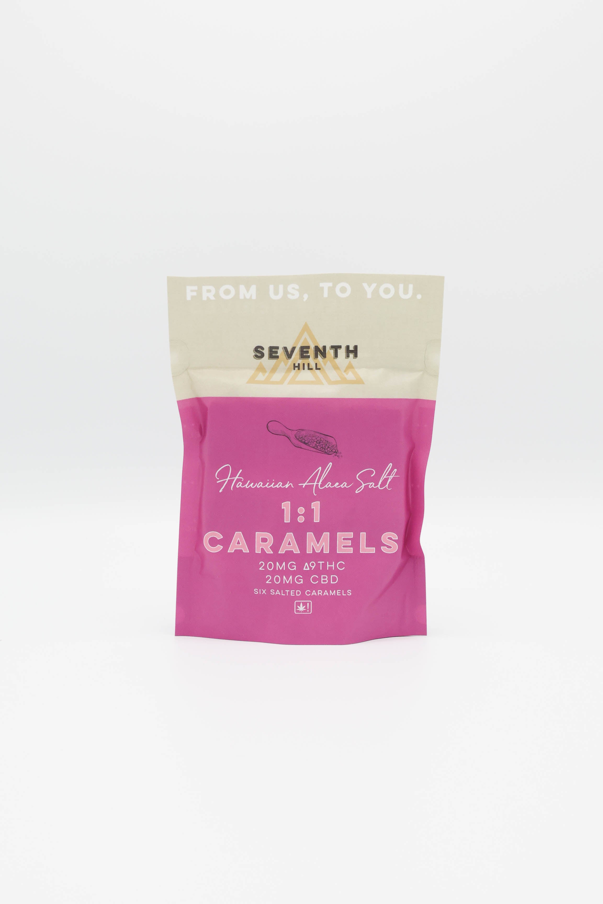 A stand-up pouch of Seventh Hill Hawaiian Alaea Salt 1:1 Caramels, featuring a bright pink lower half and a cream-colored top half with gold branding, set against a clean white background.