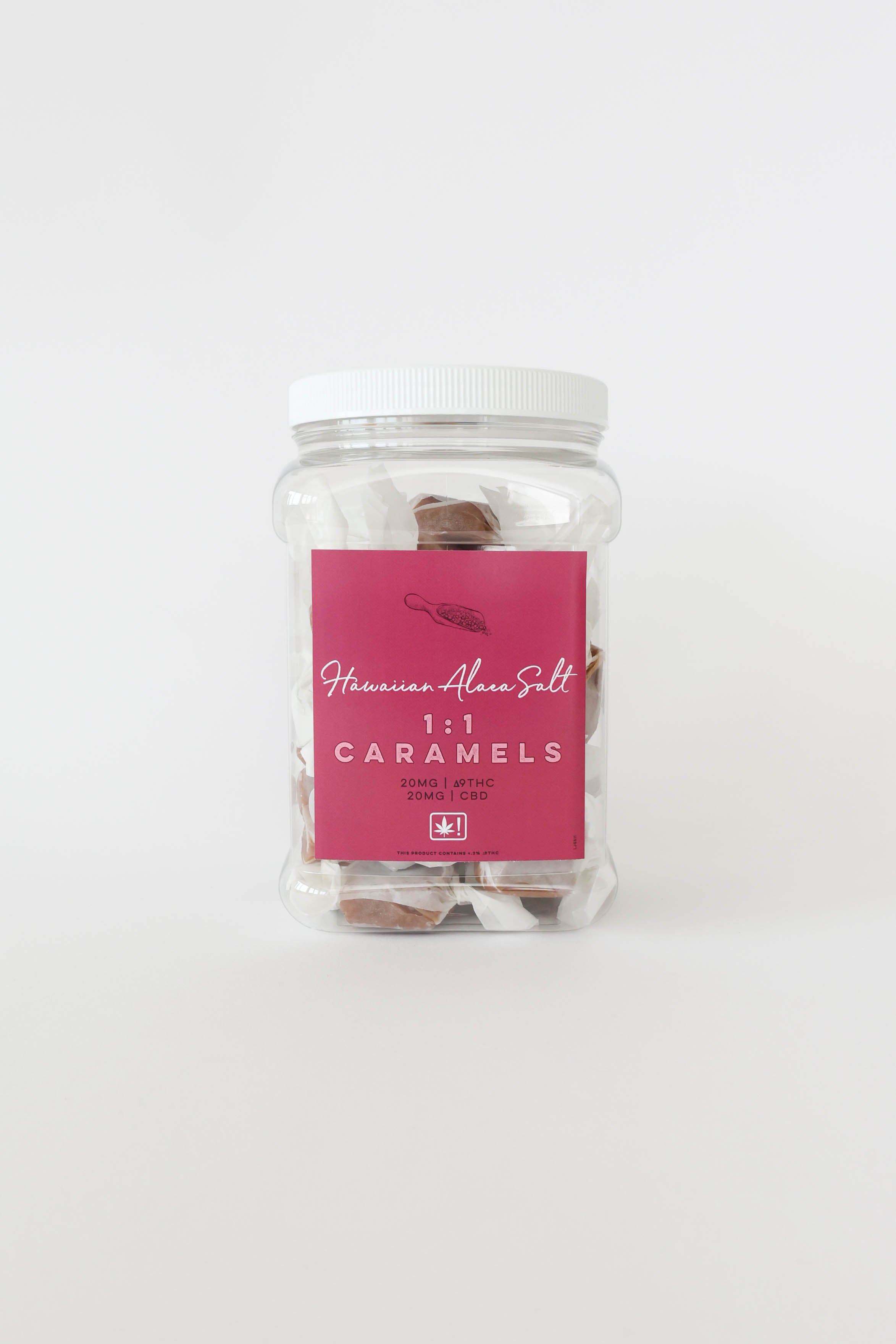 A clear plastic jar of Hawaiian Alaea Salt caramels with a white lid and a pink label, set against a plain white background.