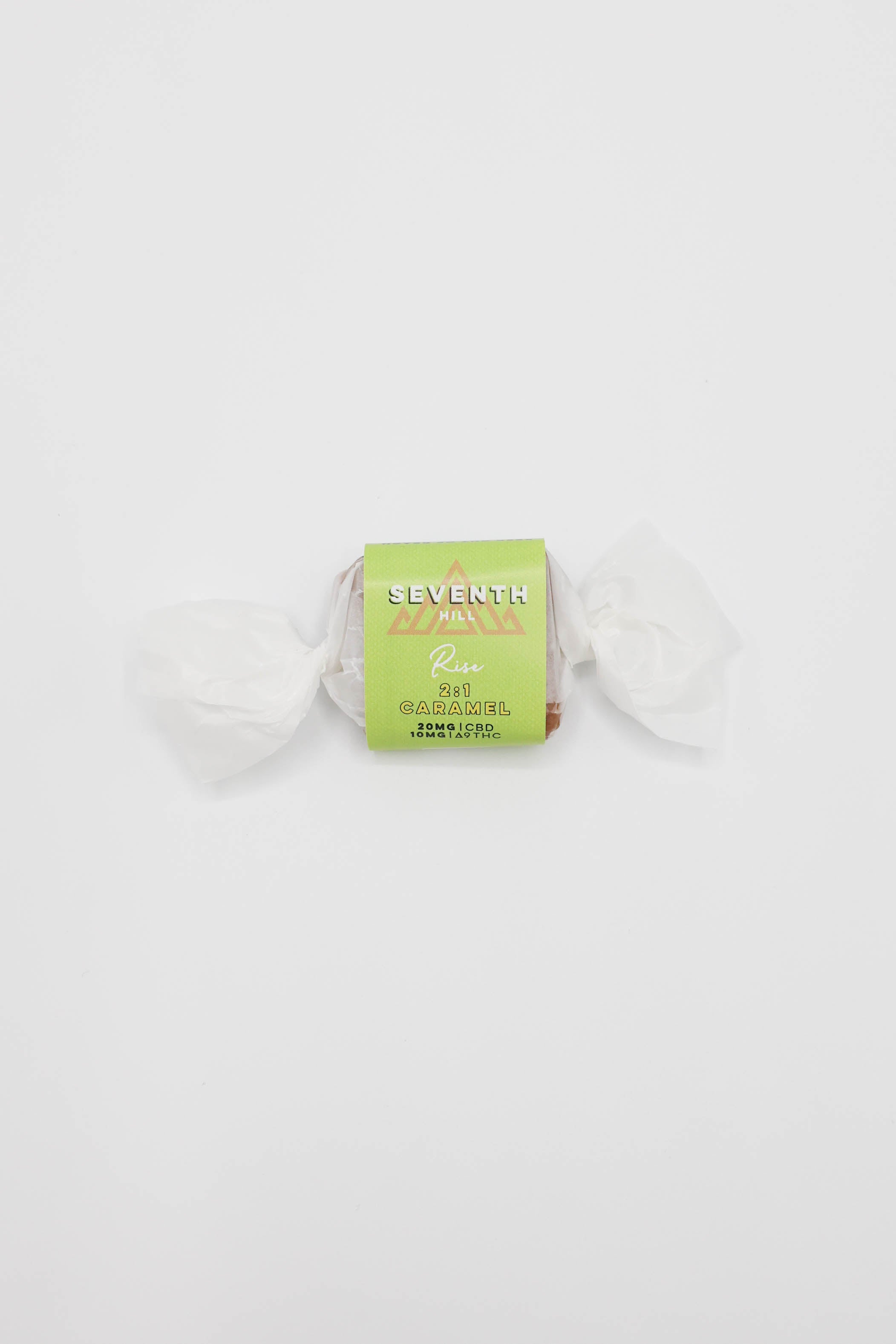 A single wrapped candy from the brand Seventh Hill, featuring a light green label with gold lettering, wrapped in white tissue paper on a solid white background.