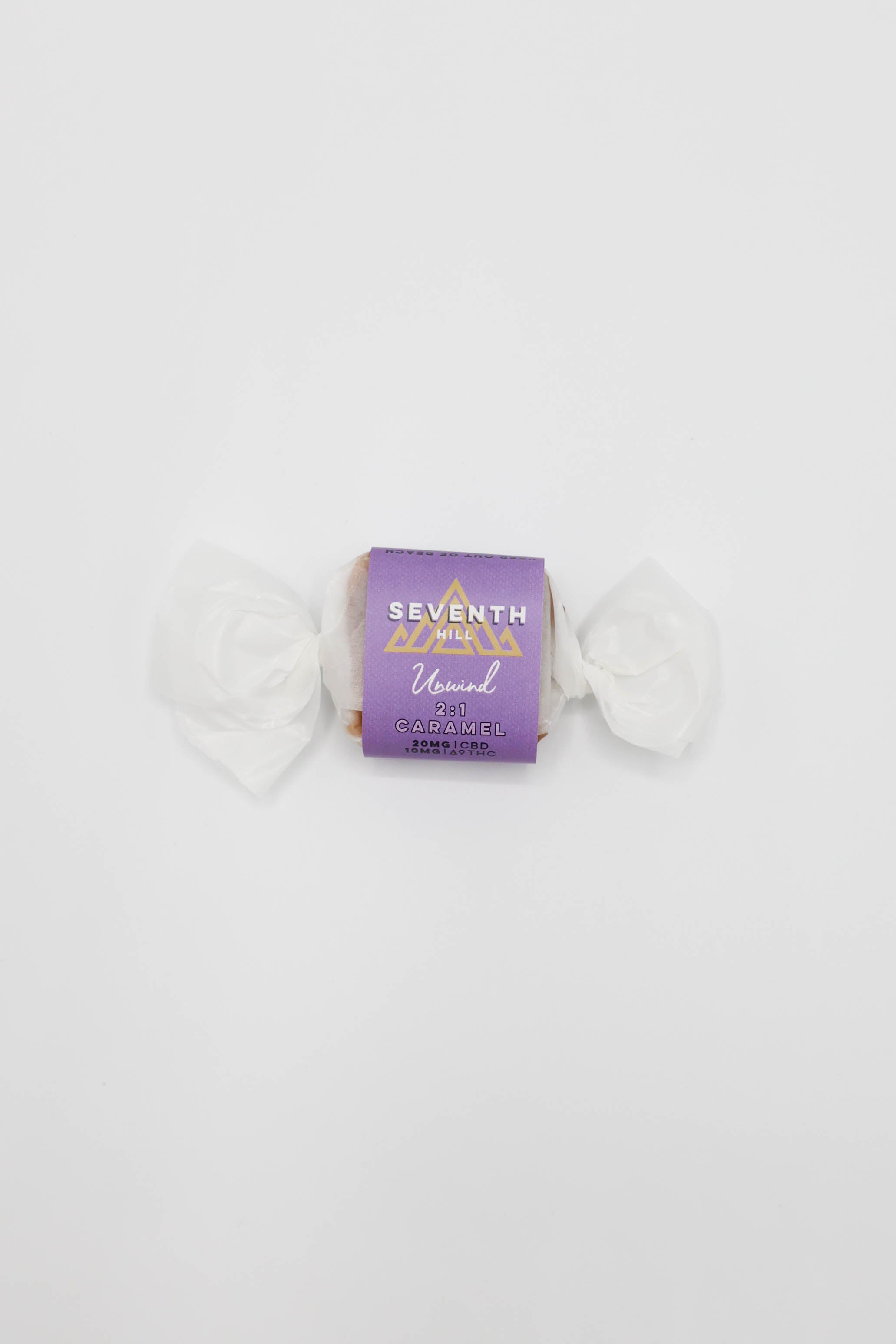 A single wrapped candy on a plain white background. The center wrapper is purple with gold lettering that reads 'SEVENTH HILL' and '2:1 Unwind Caramel"