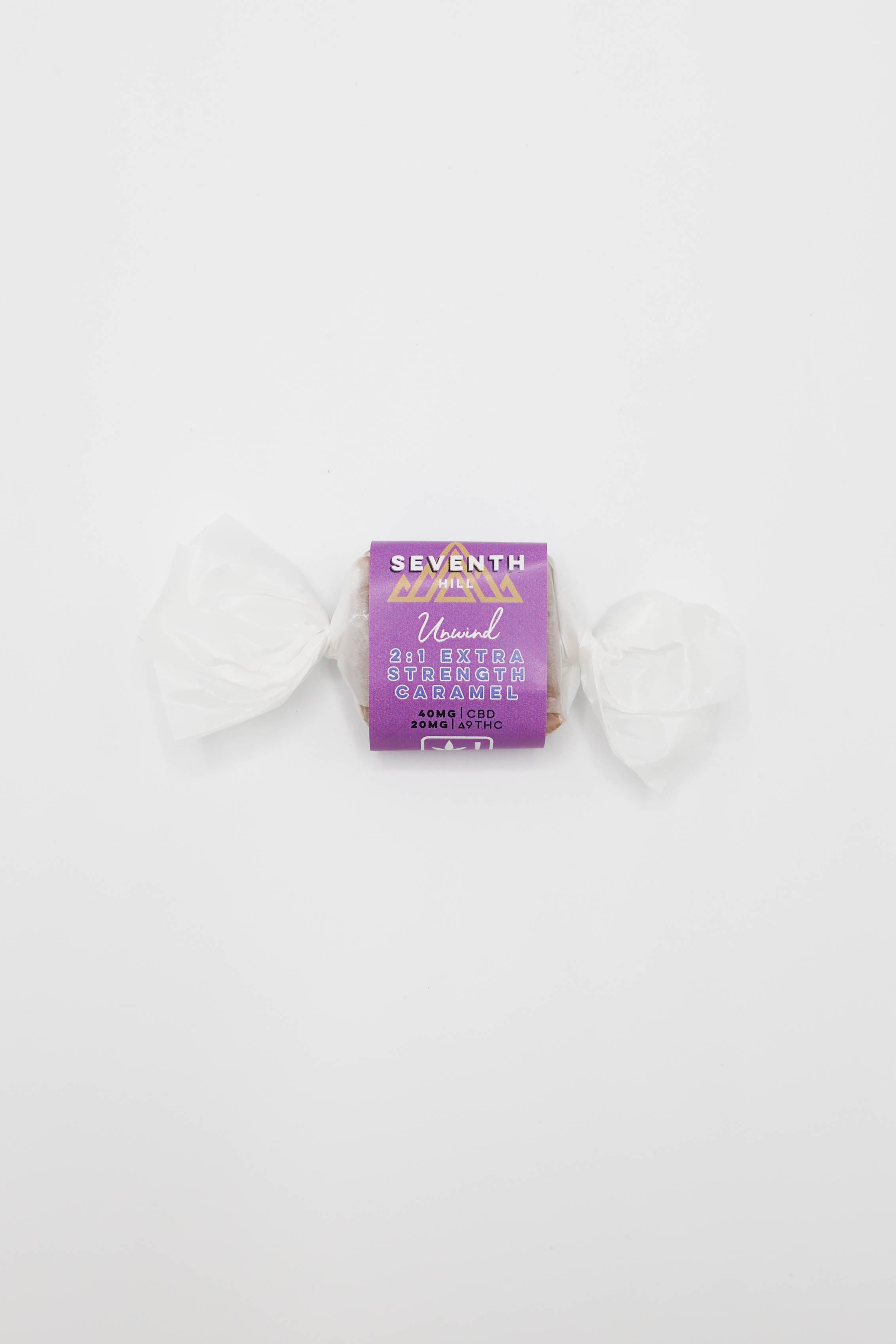 A single wrapped candy from Seventh Hill, featuring a purple wrapper with gold lettering and white wax paper wrapped around the sides, set against a plain white background.