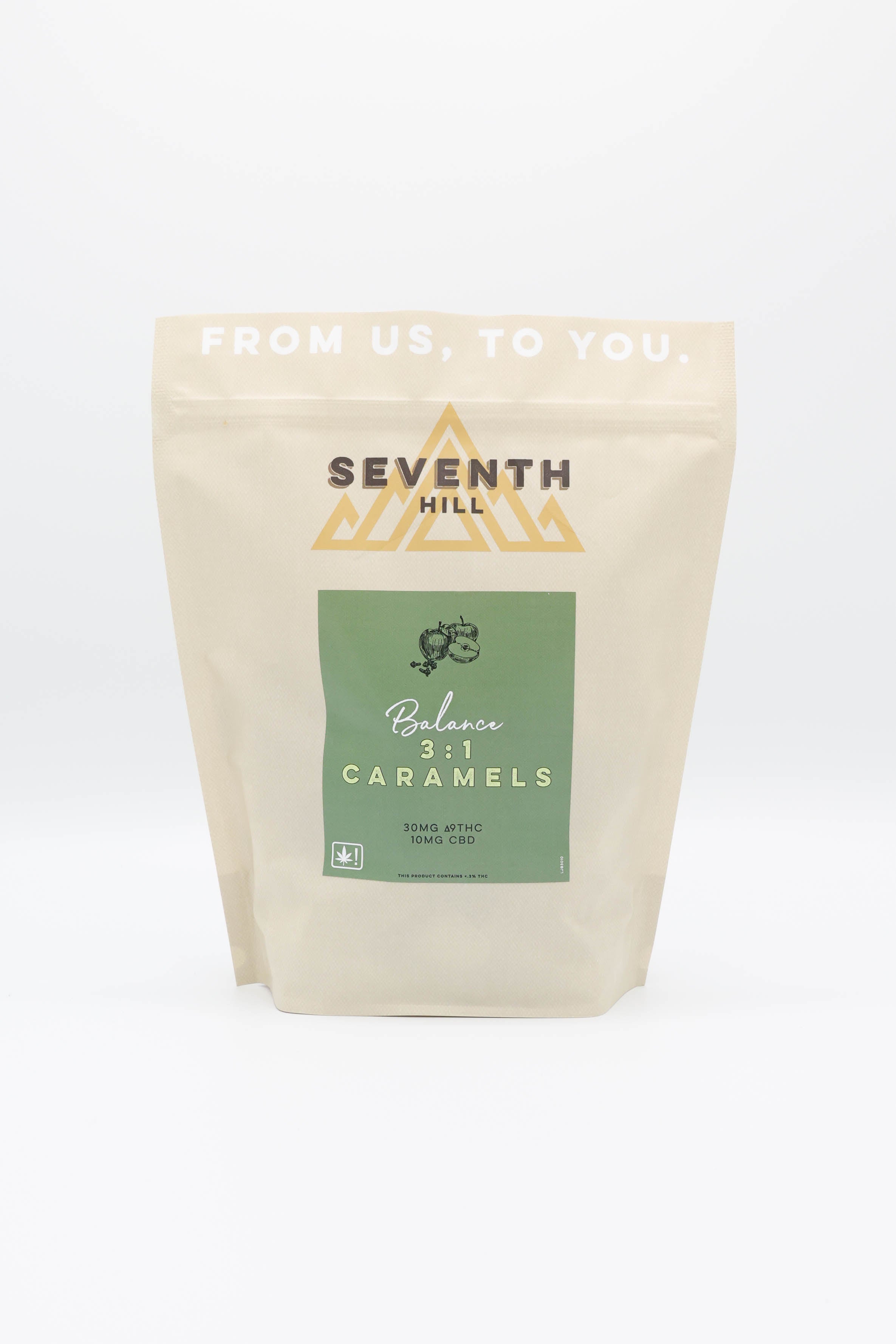 A stand-up pouch of Seventh Hill Balance 3:1 Caramels on a clean white background. The packaging is a light beige kraft paper style with a green label in the center and gold geometric logo details.