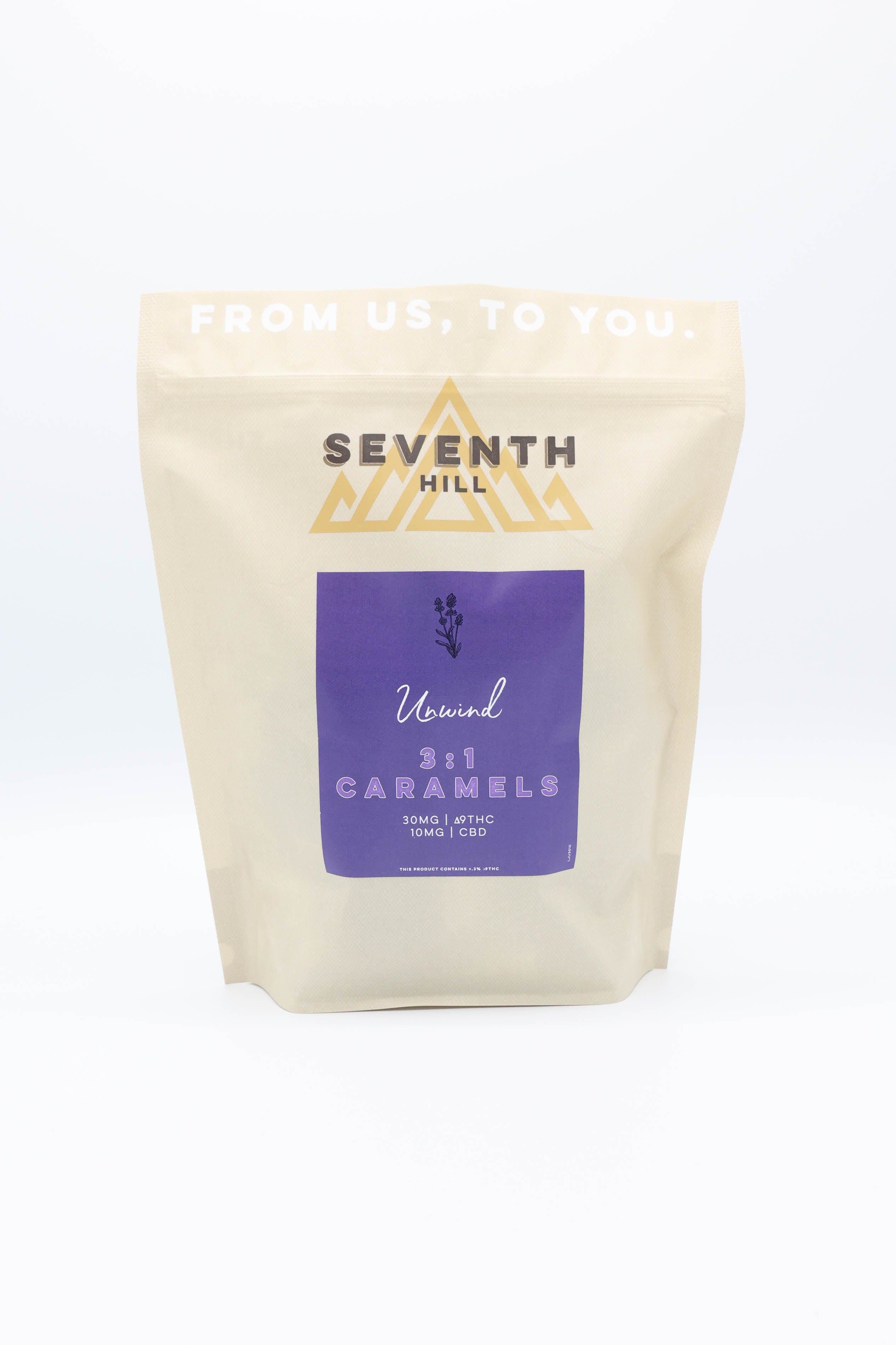 A stand-up pouch of Seventh Hill Caramels, Unwind 3:1 Caramels, on a clean white background. The pouch is a warm cream color with a purple label and gold logo.