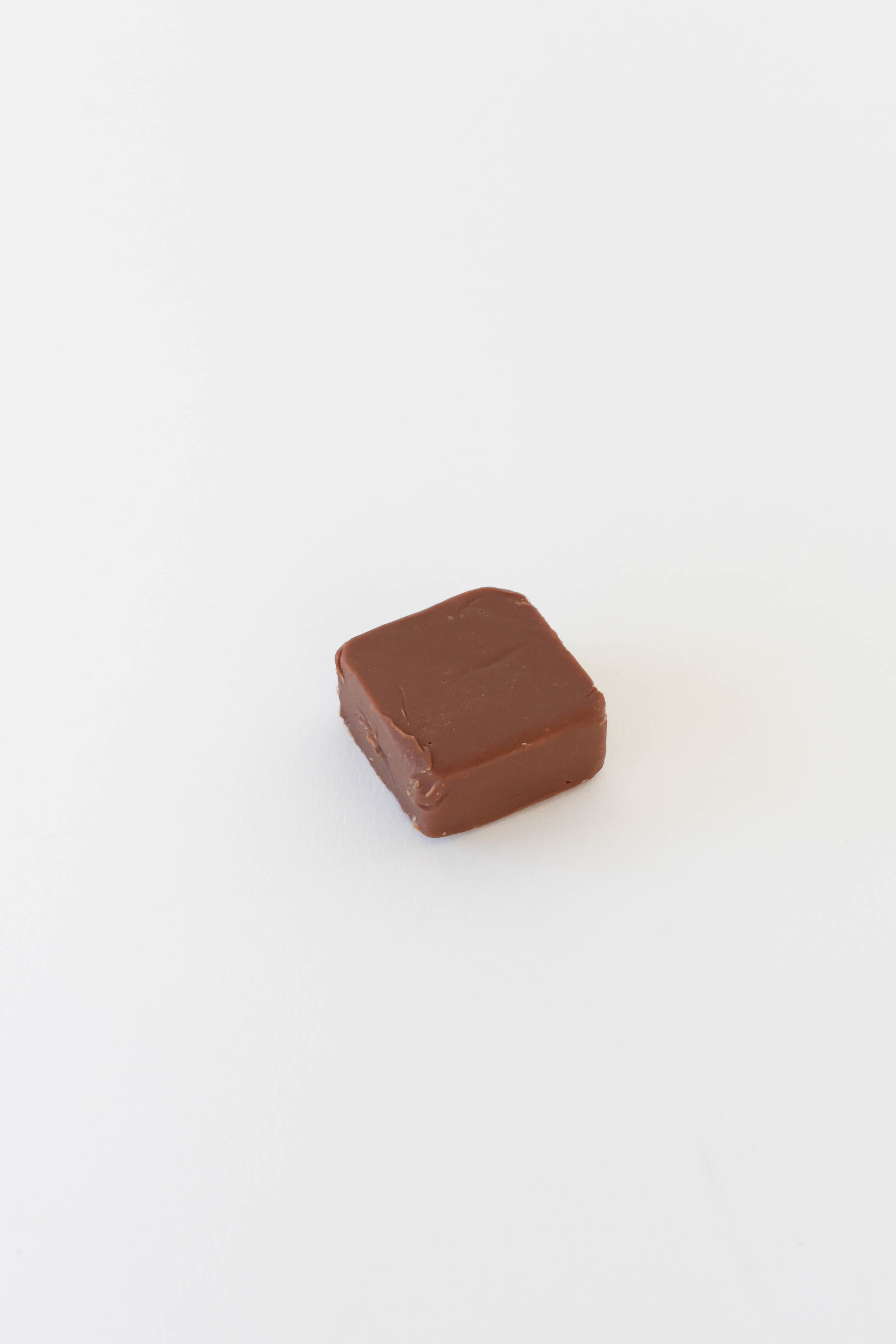 A single square piece of dark chocolate with a smooth, glossy surface, centered on a plain white background.