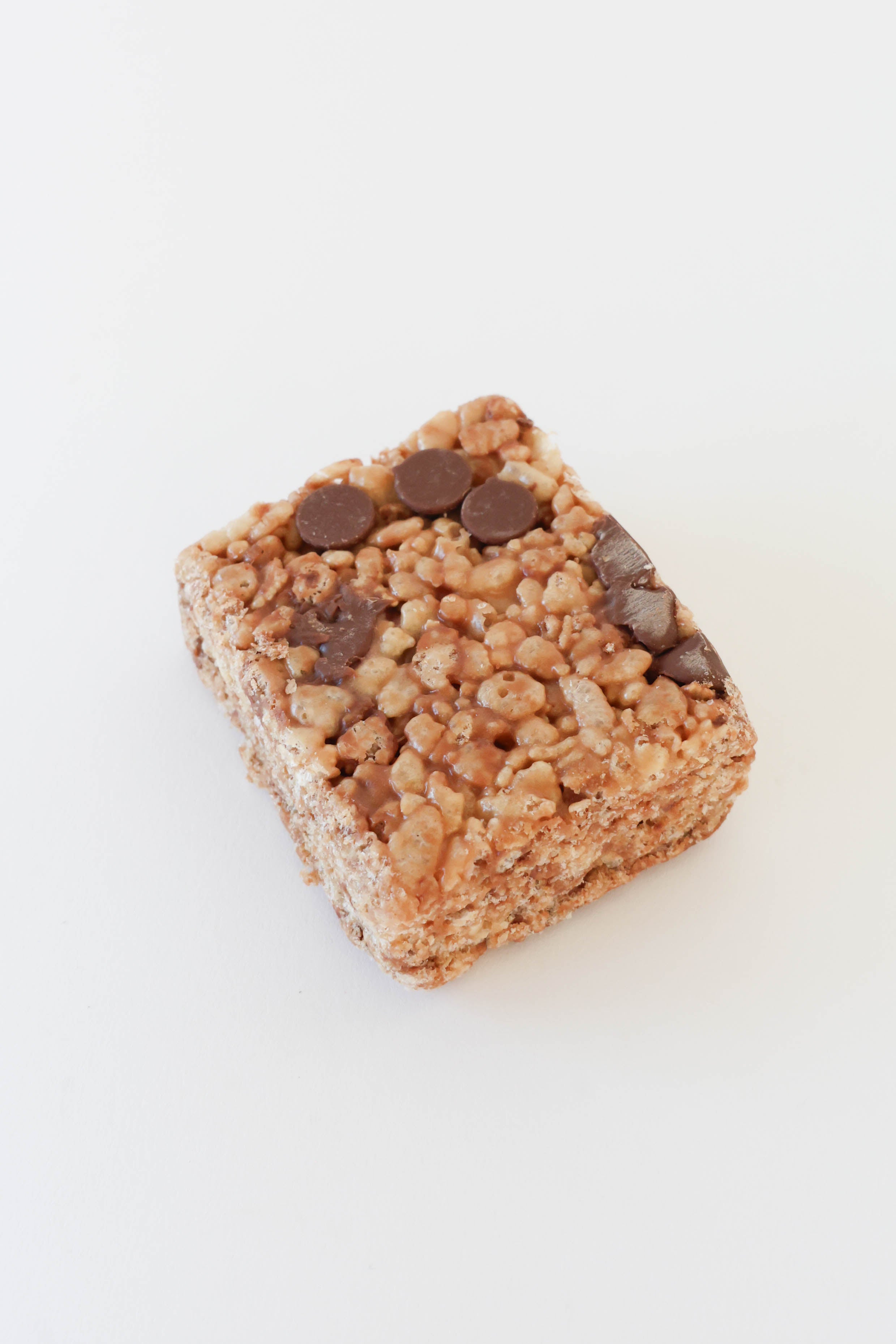 A single square rice krispie treat bar with chocolate chips, photographed on a clean white background.