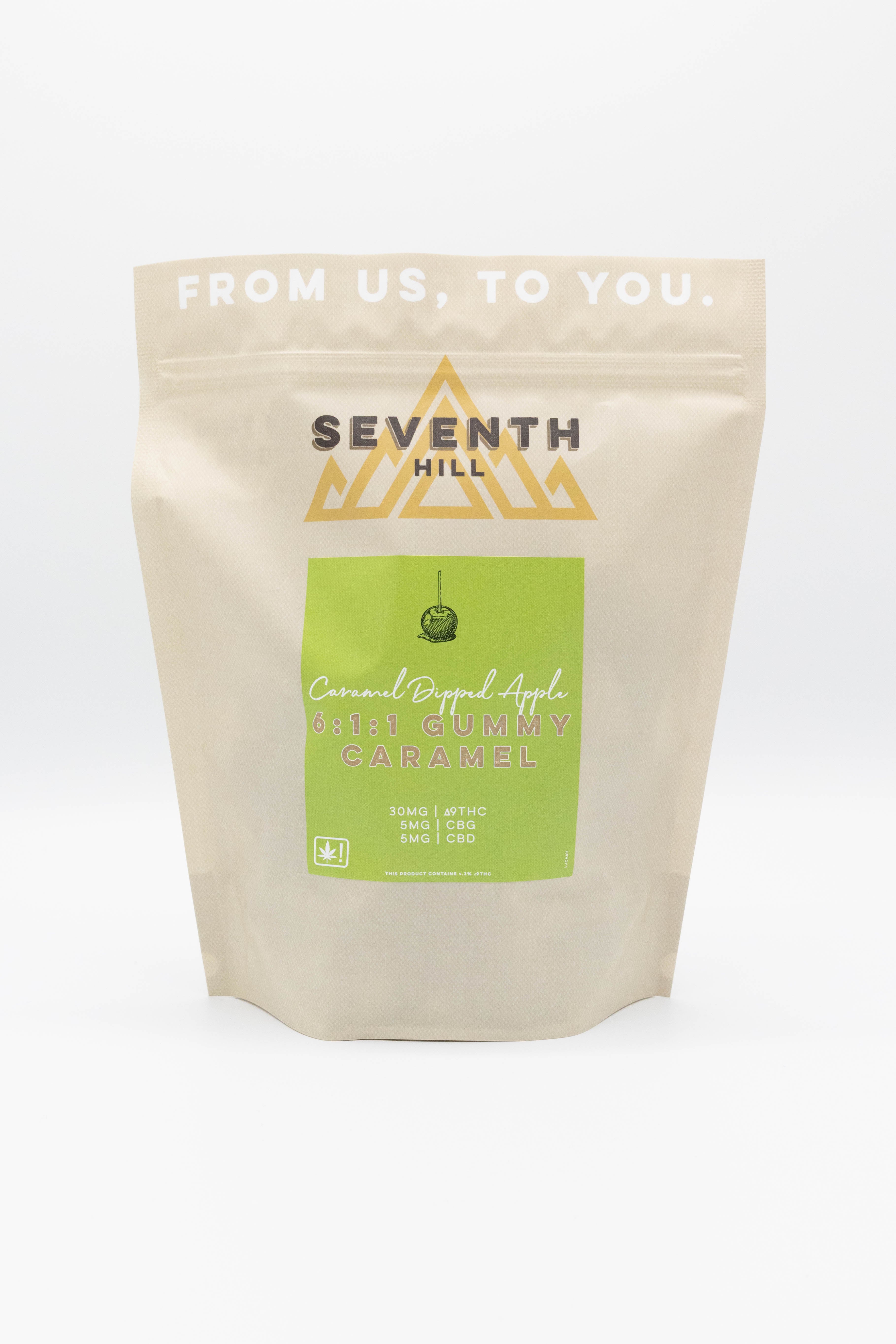 A stand-up pouch of Seventh Hill Caramel Apple Gummy Candy on a clean white background. The pouch is a warm cream color with a lime green label and gold logo.