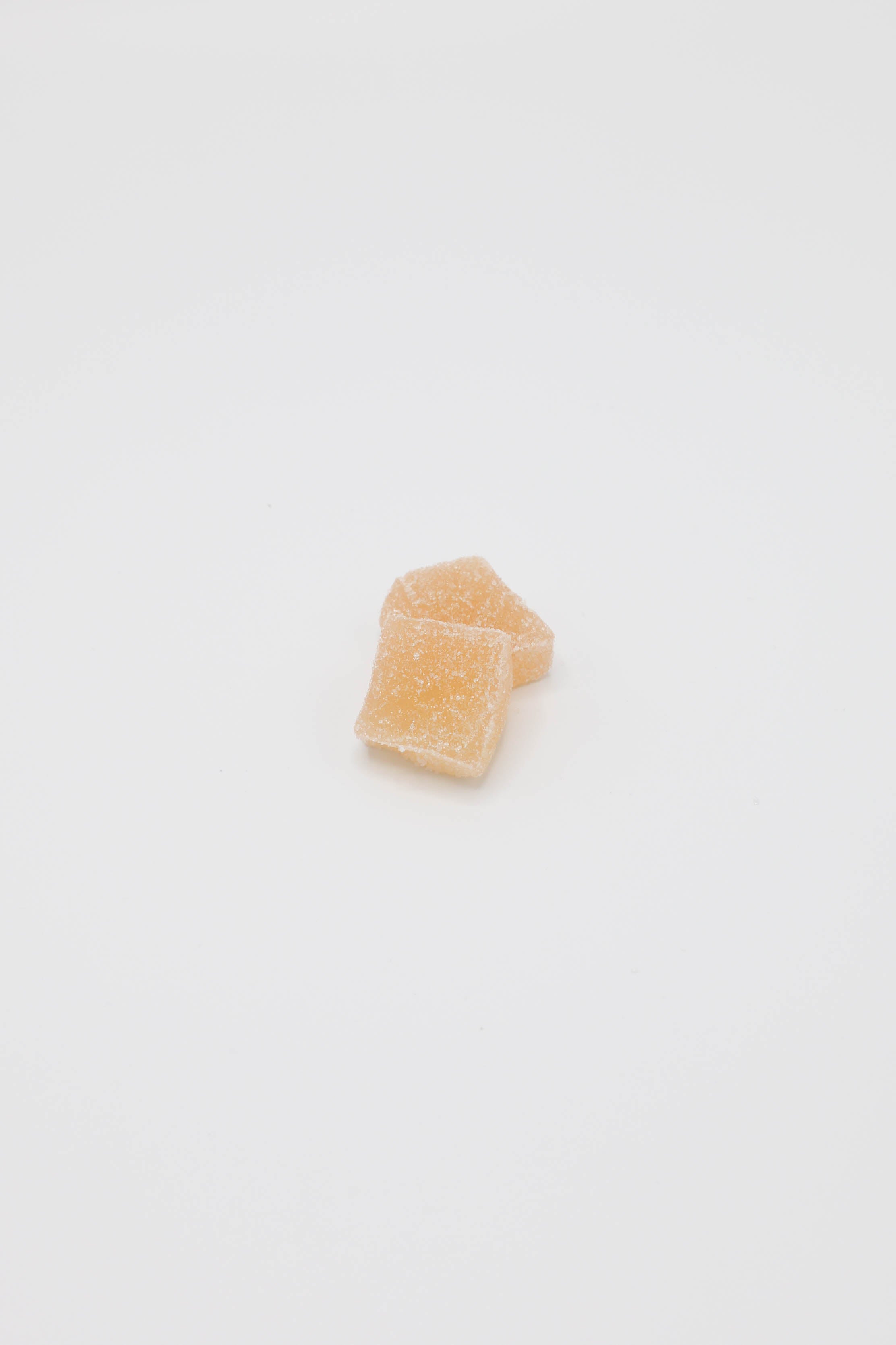 Two small, translucent yellow-colored sugar cubes on a plain white background.