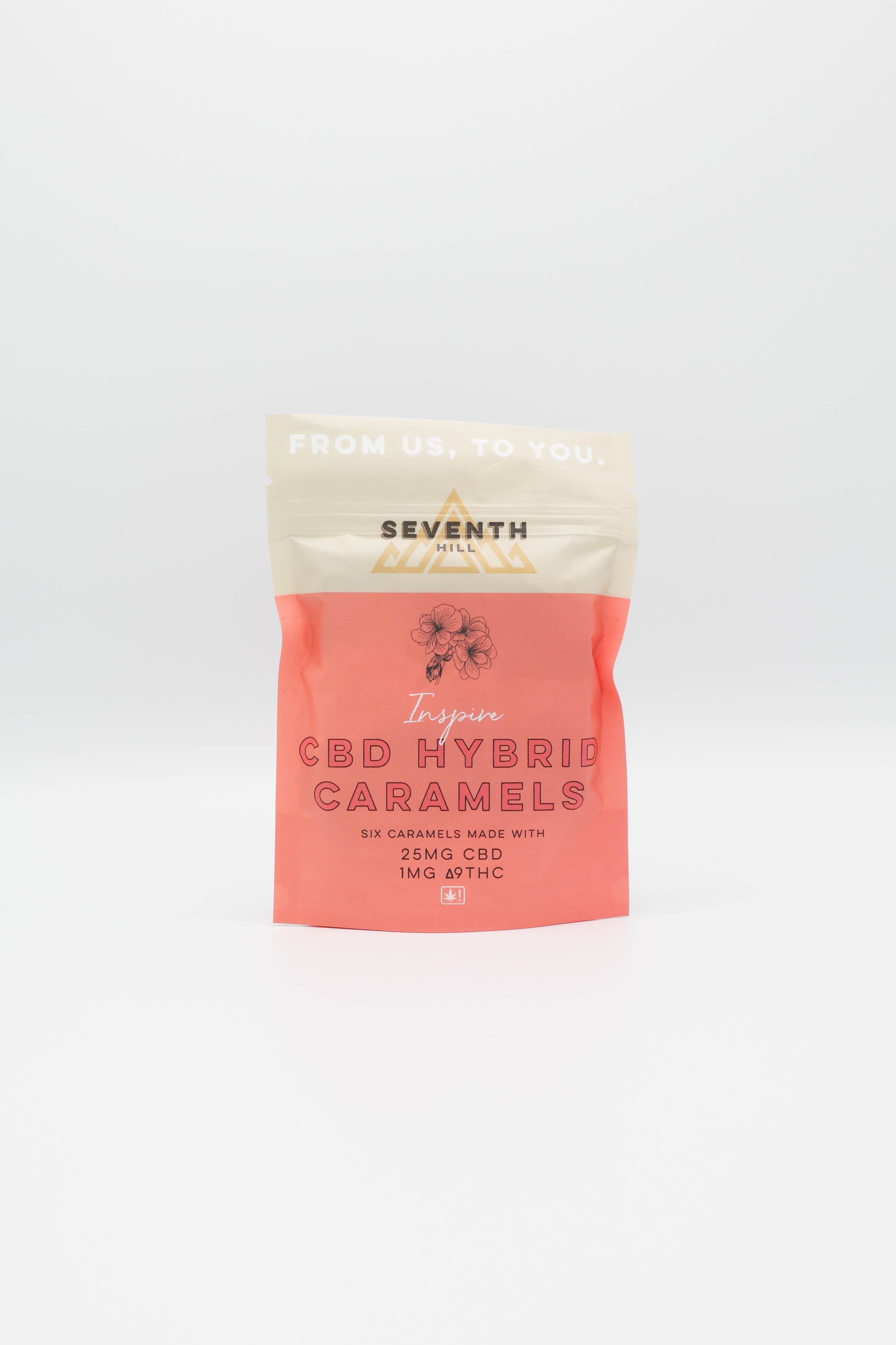 A stand-up pouch of Seventh Hill 'Inspire' CBD Hybrid Caramels, featuring a coral pink lower half and a cream upper half with gold branding, set against a seamless white background.