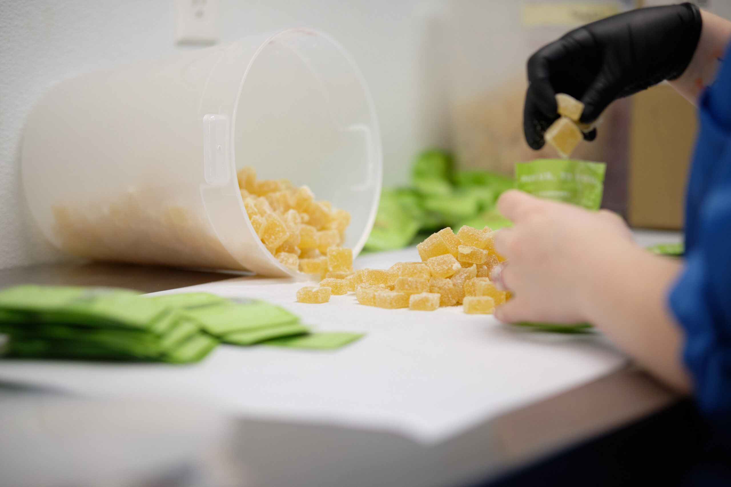 A pile of organic dye-free gummies are being placed into their packaging by hand.