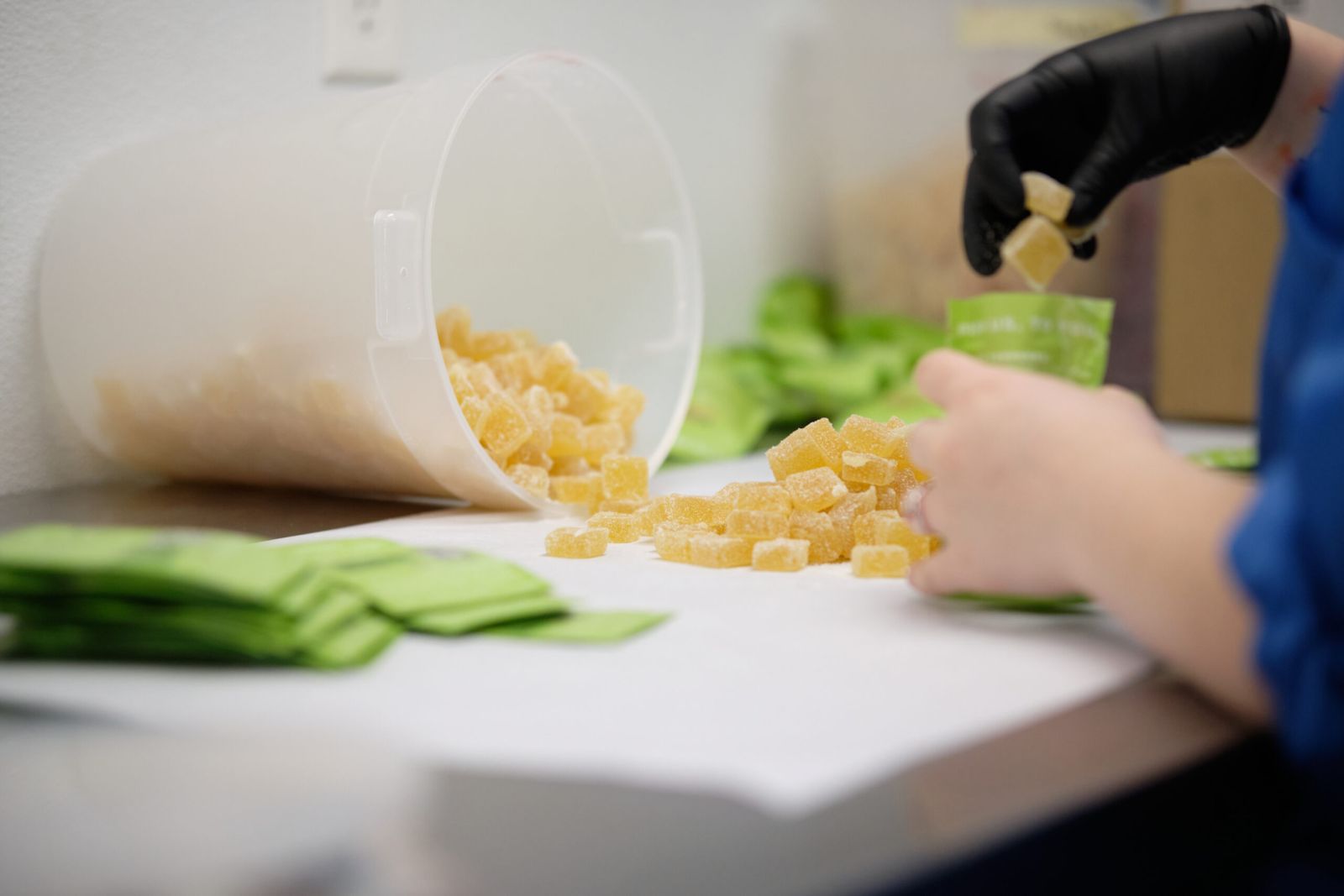A pile of organic dye-free gummies are being placed into their packaging by hand.
